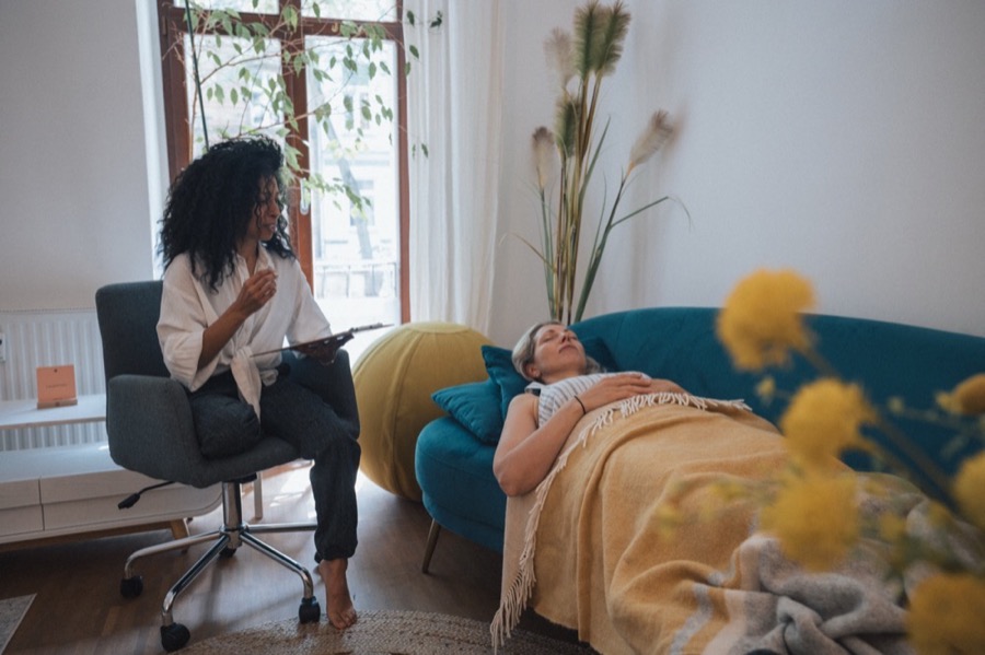 A client resting under a yellow blanket during hypnosis